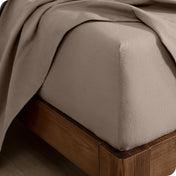 A close up of a corner of a modern bed with a flannel fitted sheet on.