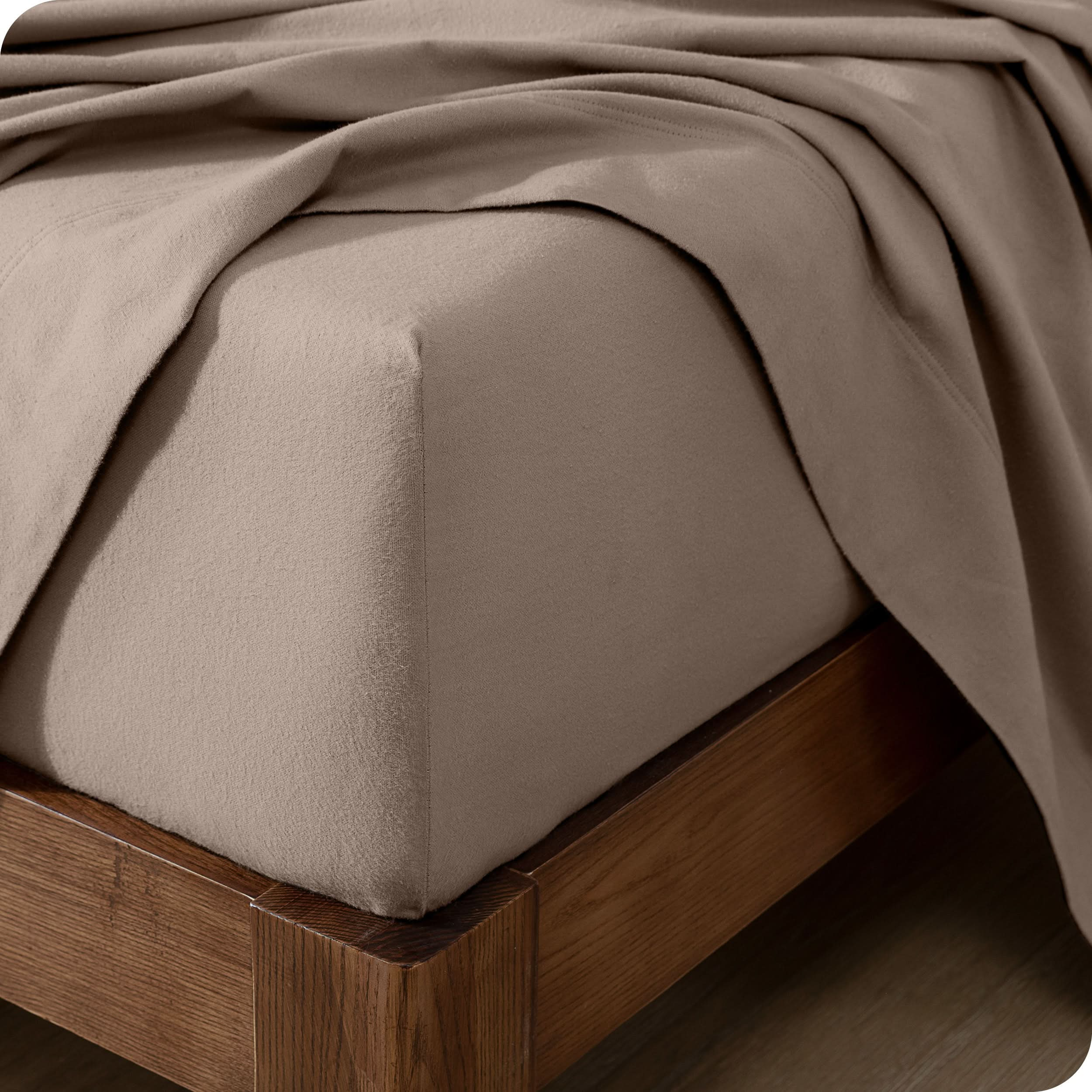 Close up of the corner of a mattress with a flannel fitted sheet and flat sheet on it