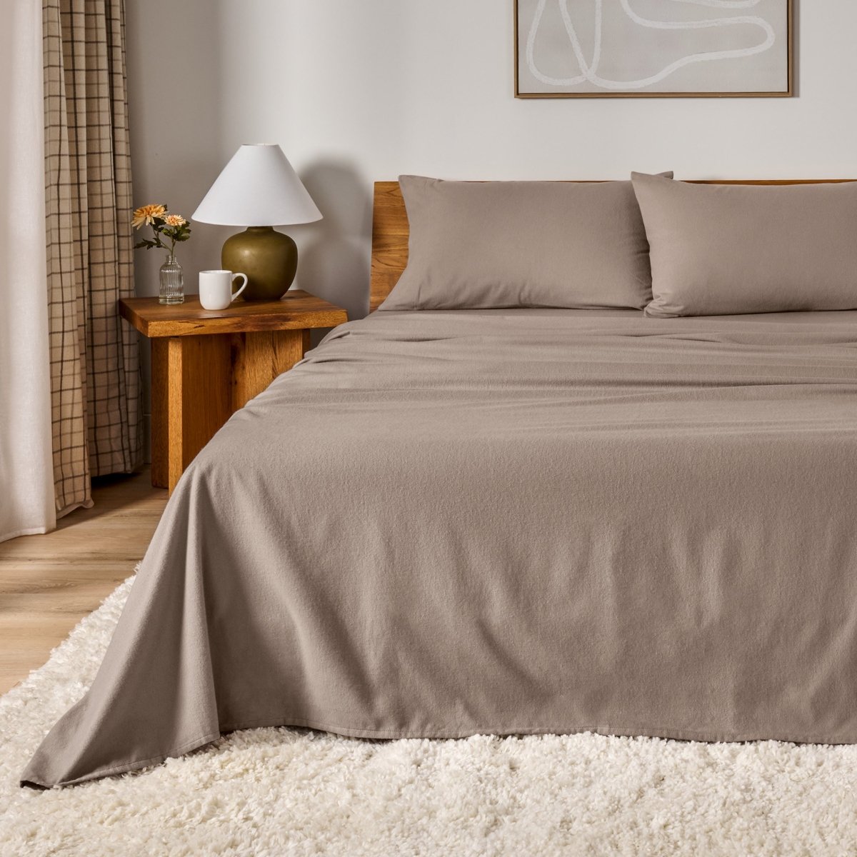 Cotton flannel sheet set on a bed in a bedroom setting with a lamp and decor.