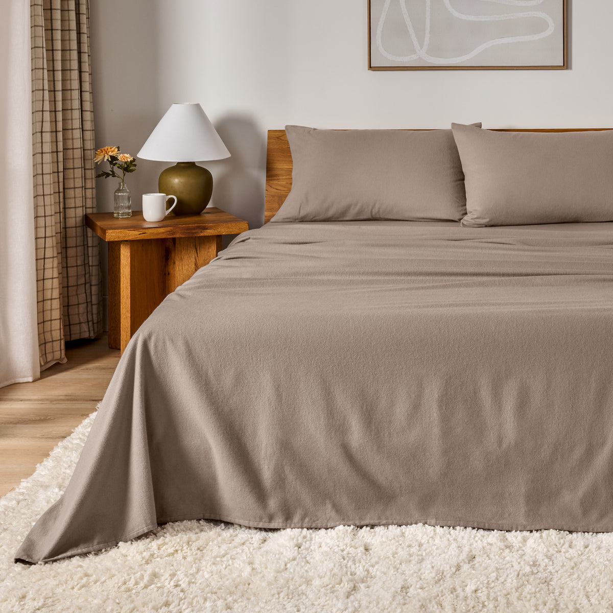 A bed dressed in flannel sheet set in a bedroom with a wooden headboard, bedside table and lamp