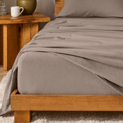 Bed with flannel bedding and wooden headboard and nightstand next to it.