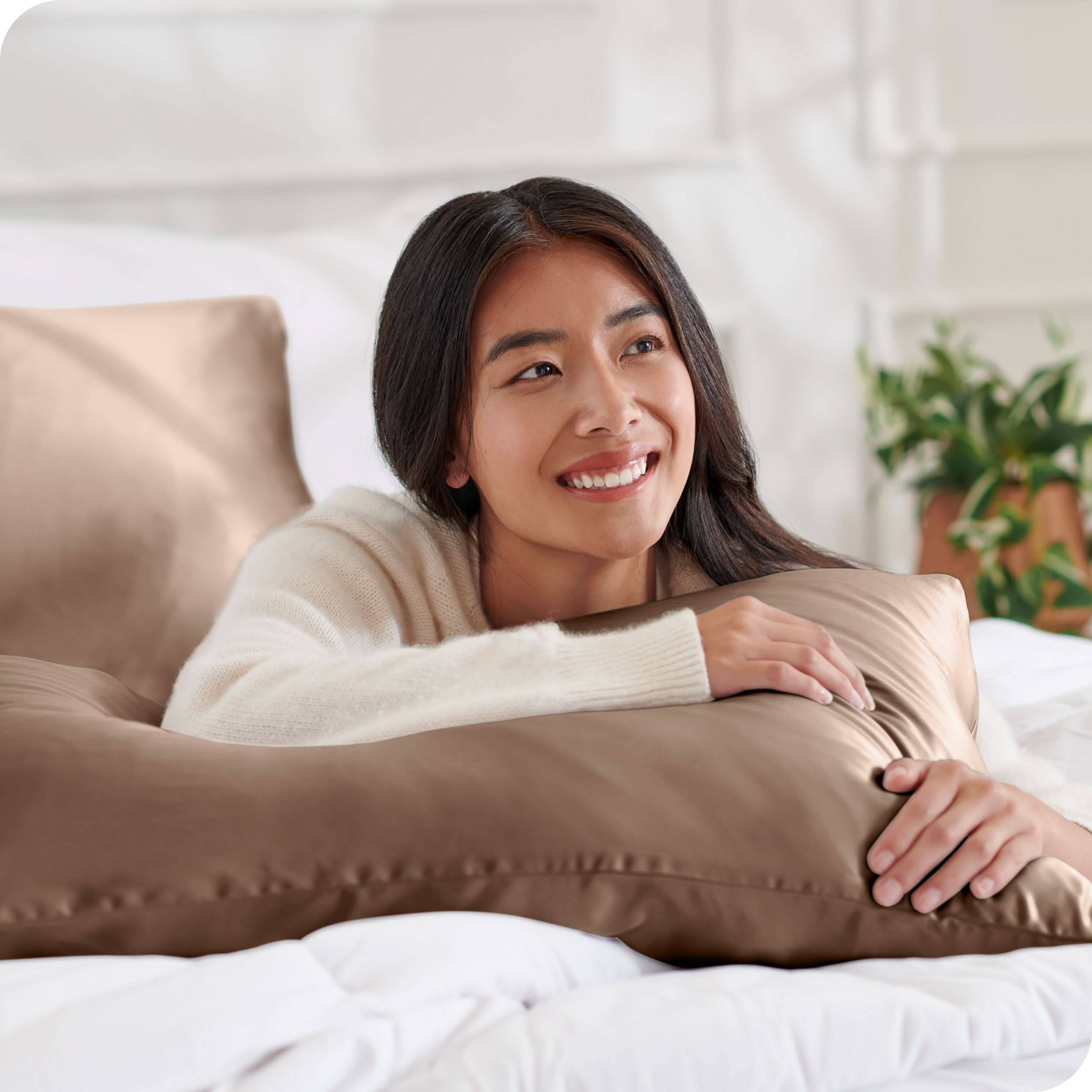 A woman on a bed with a silk pillowcase covered pillow