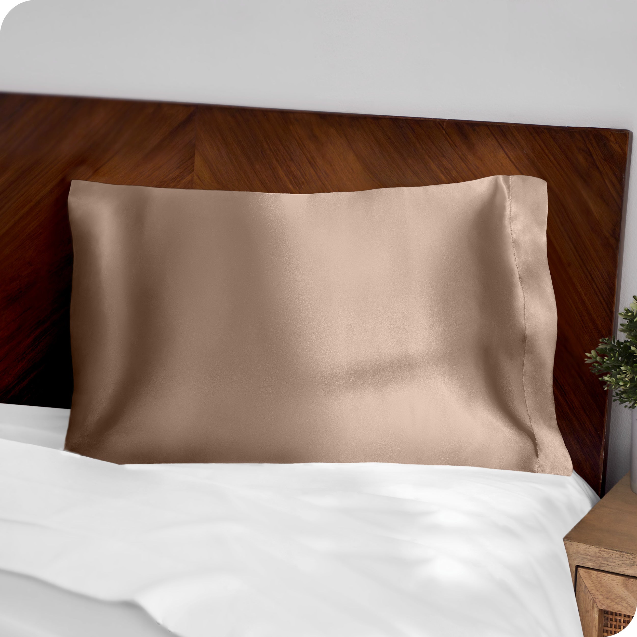 A brown silk pillowcase on a pillow resting on a headboard