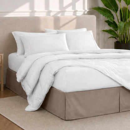 A modern bedroom with a bed skirt, comforter and sheets on the bed