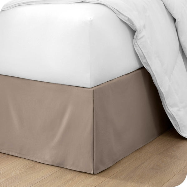 The corner of a bed with a bed skirt and comforter on it