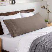 Bed sheets and pillows on a neatly made bed with a wooden headboard.