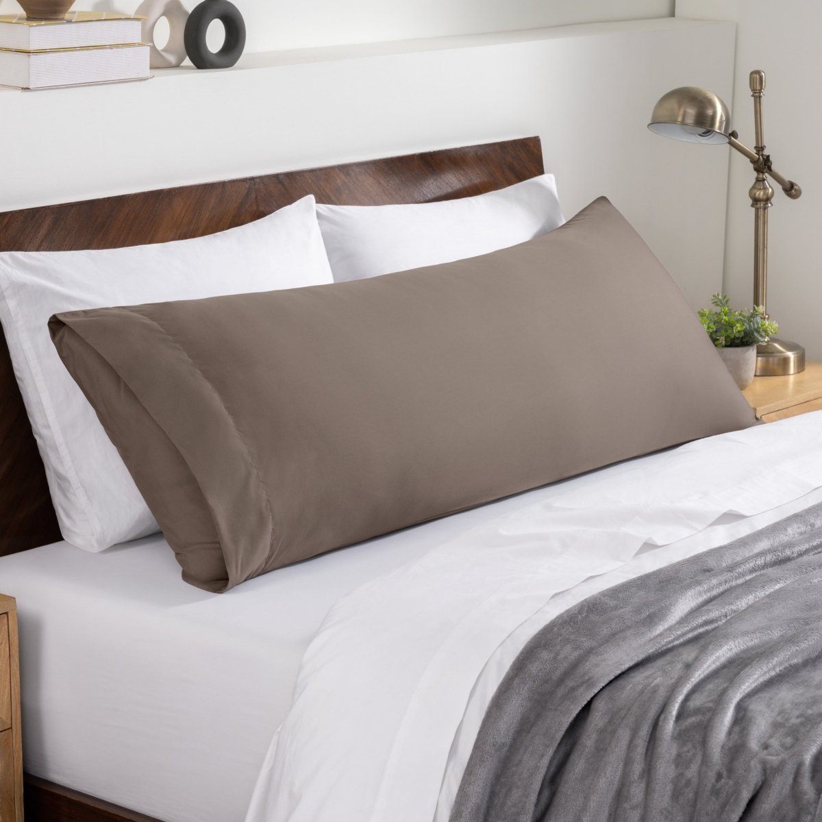 Bed sheets and pillows on a neatly made bed with a wooden headboard.
