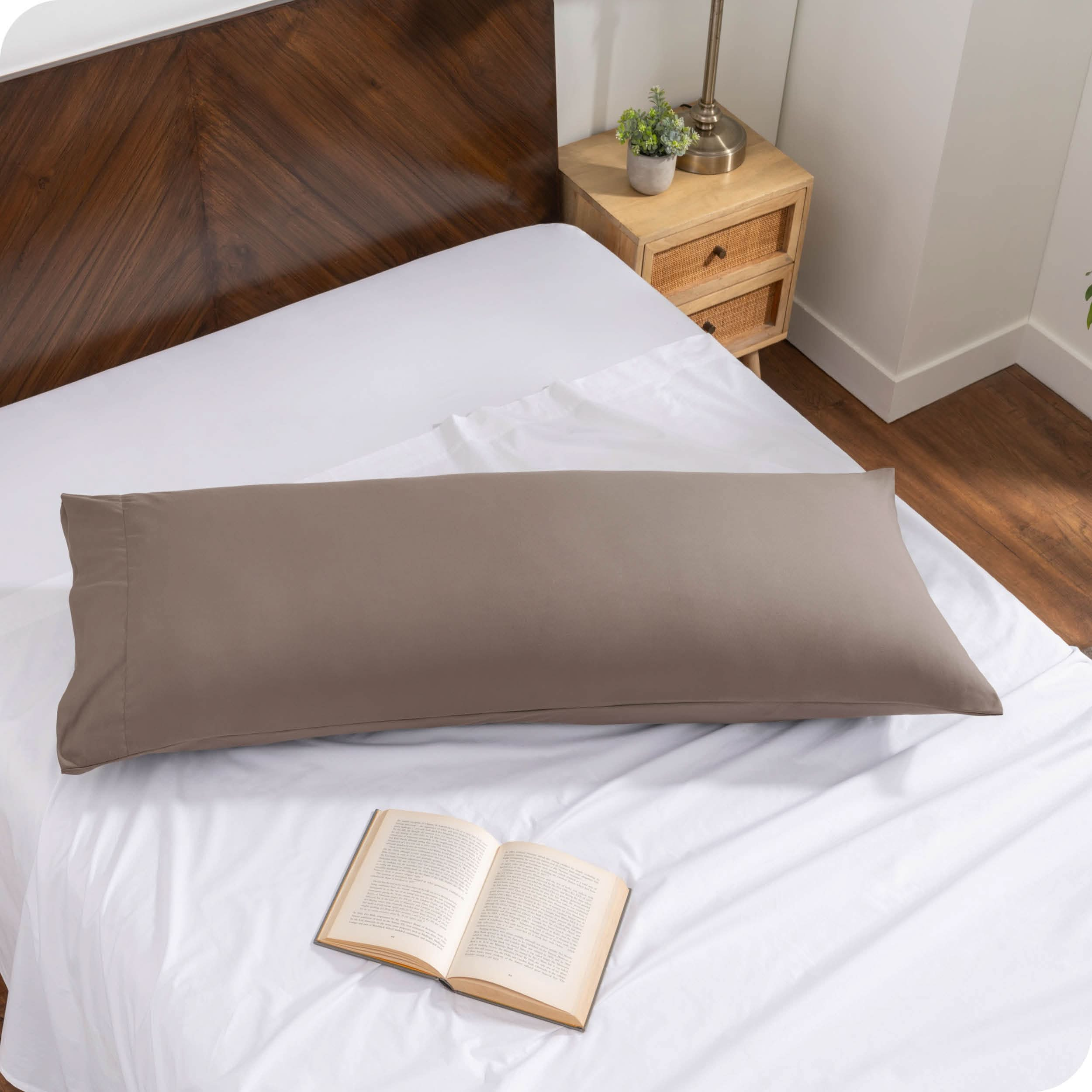 A body pillow cover on a pillow on a bed made with all white bedding