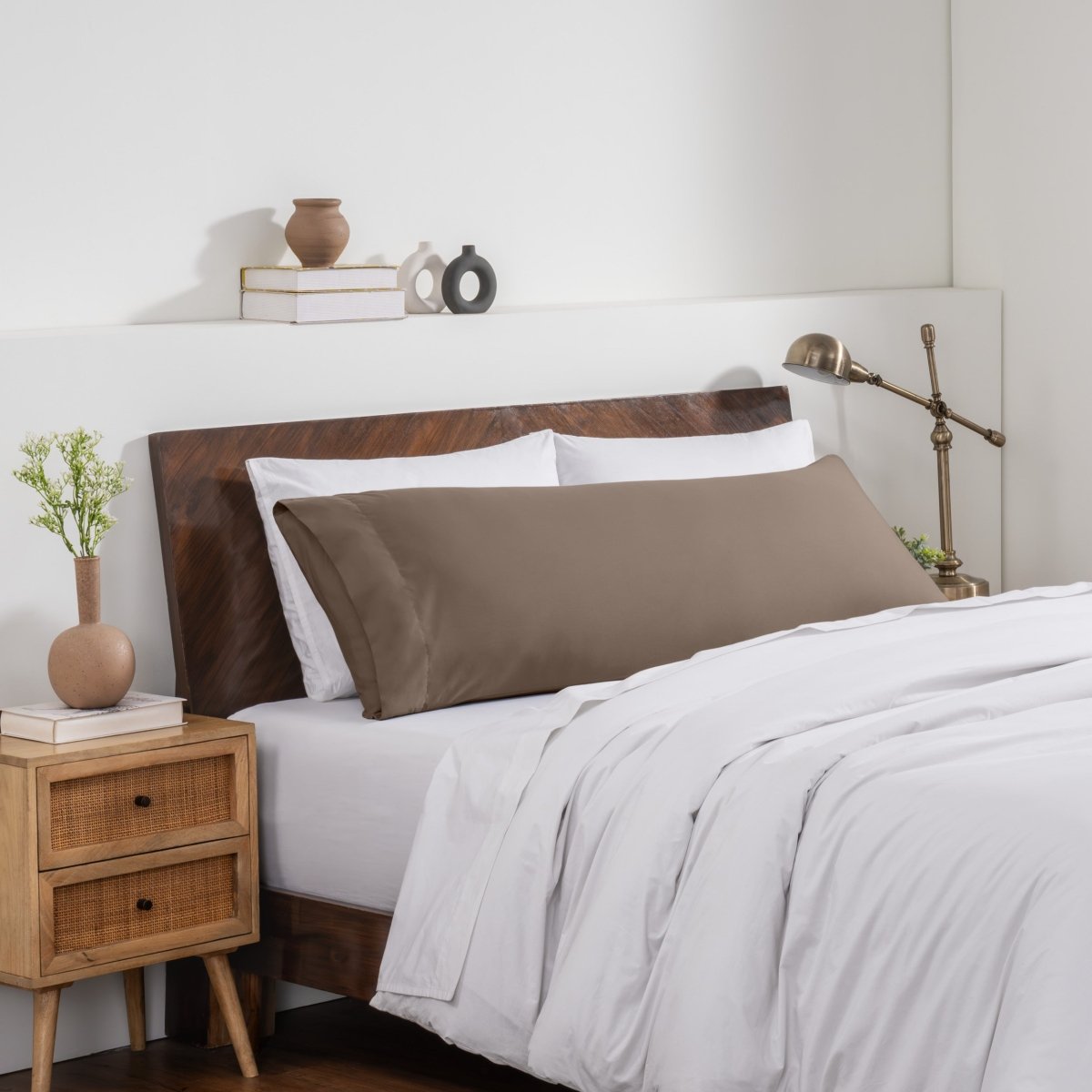 Bedroom with a wooden headboard and white bedding, featuring a nightstand and decorative items.