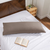 Pillowcase on a body pillow with a wooden headboard and plant in the background