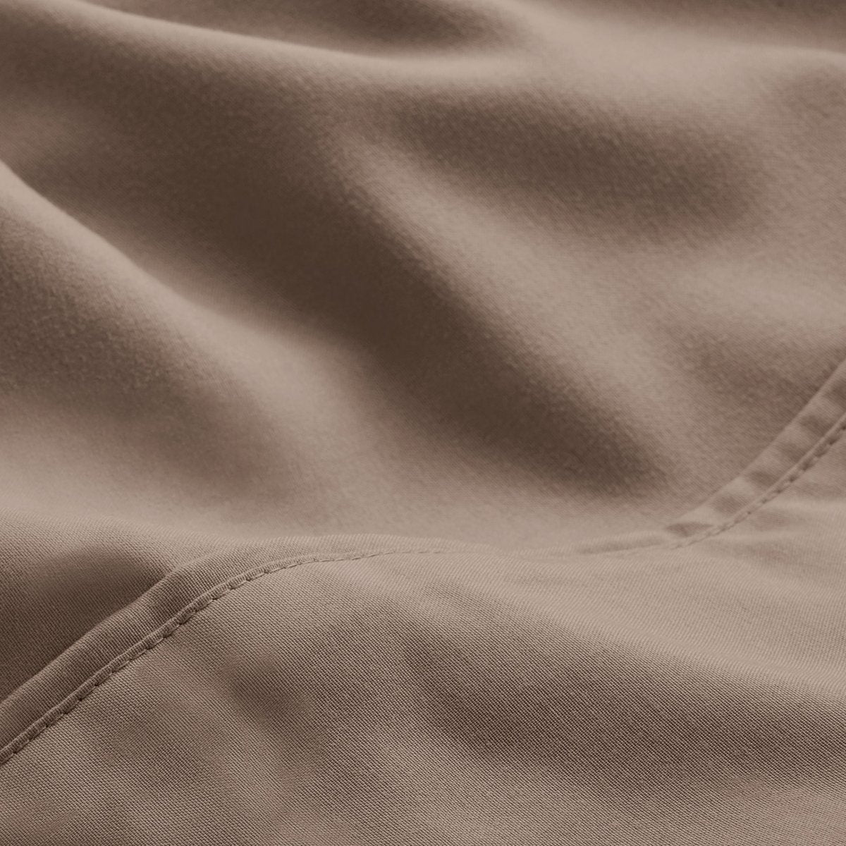 A close-up of microfiber fabric with soft folds and a visible stitched seam.