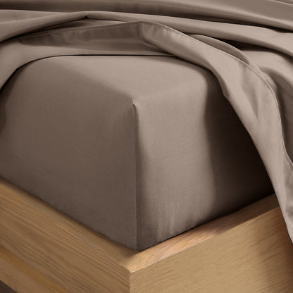 A close-up of a fitted sheet covering the corner of a bed frame, with matching top sheet draped over it.