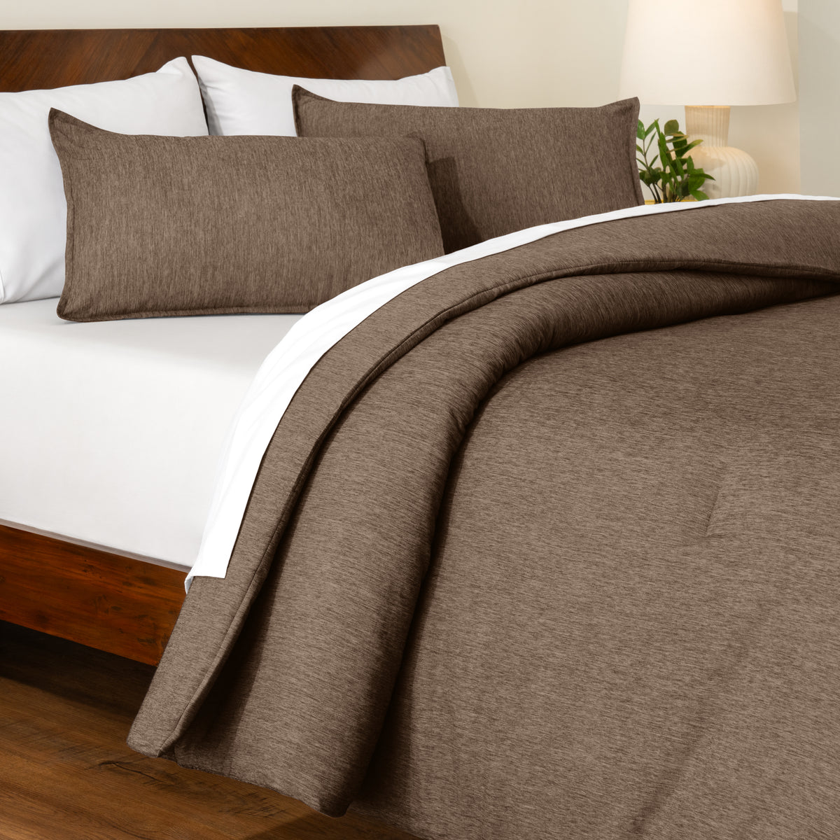 Track stitch comforter on a bed with white pillows and a wooden headboard.