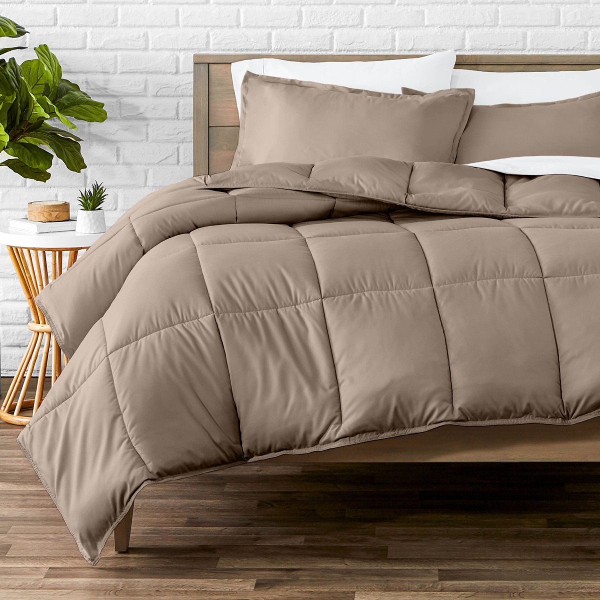 Comforter set on a bed with a white brick wall and plant in the background