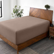 A diagonal view of a bed with just a fitted sheet on it