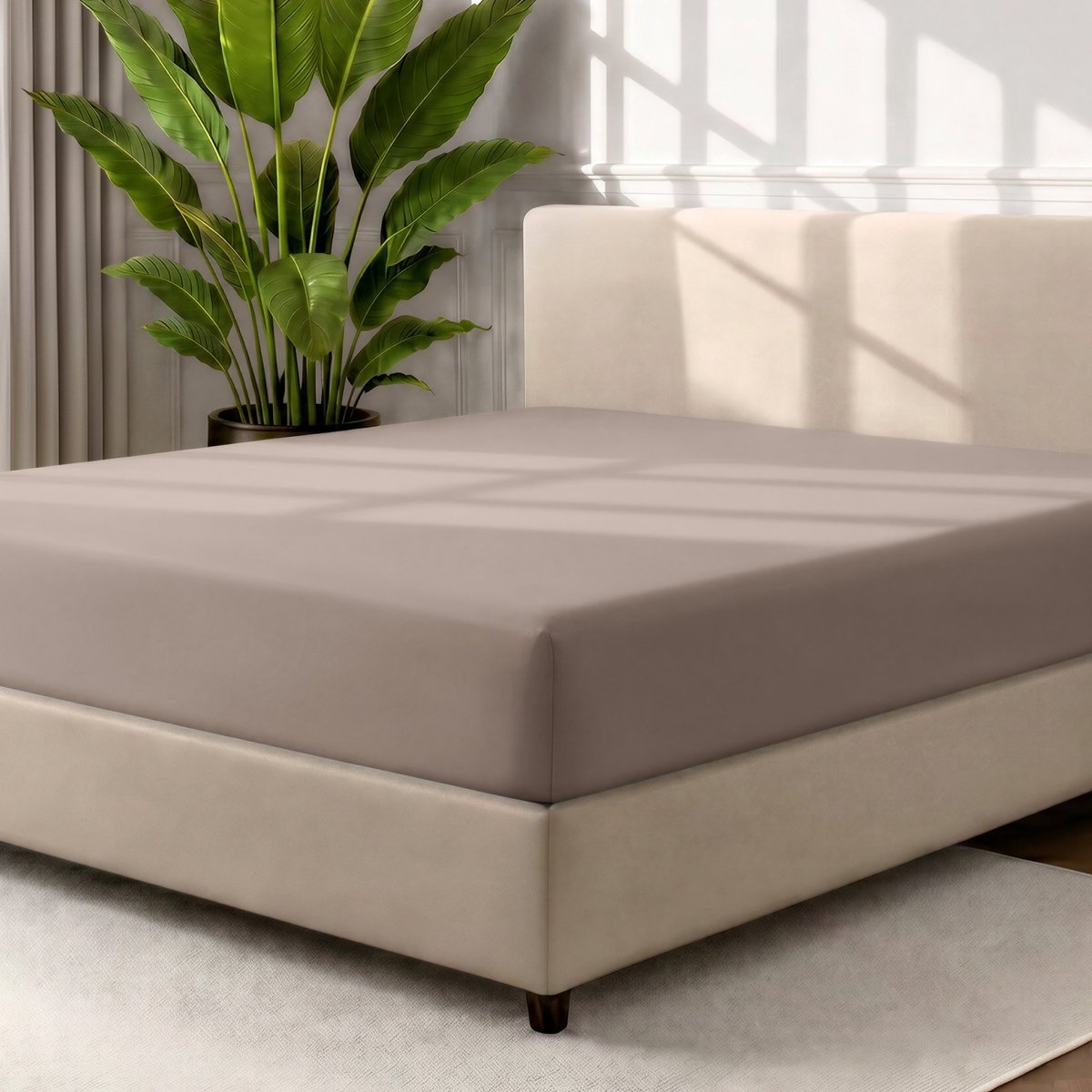 A fitted sheet covering a bed with a cream colored frame, styled in a bedroom setting with a large potted plant.