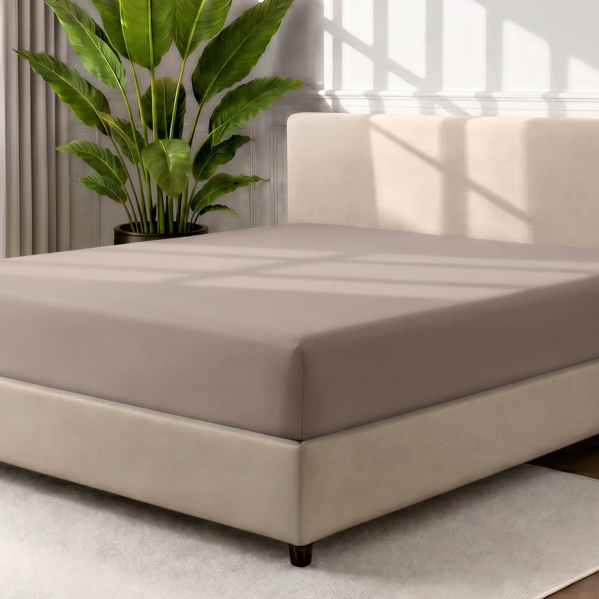 Man adjusting fitted sheet on a bed with white pillows.