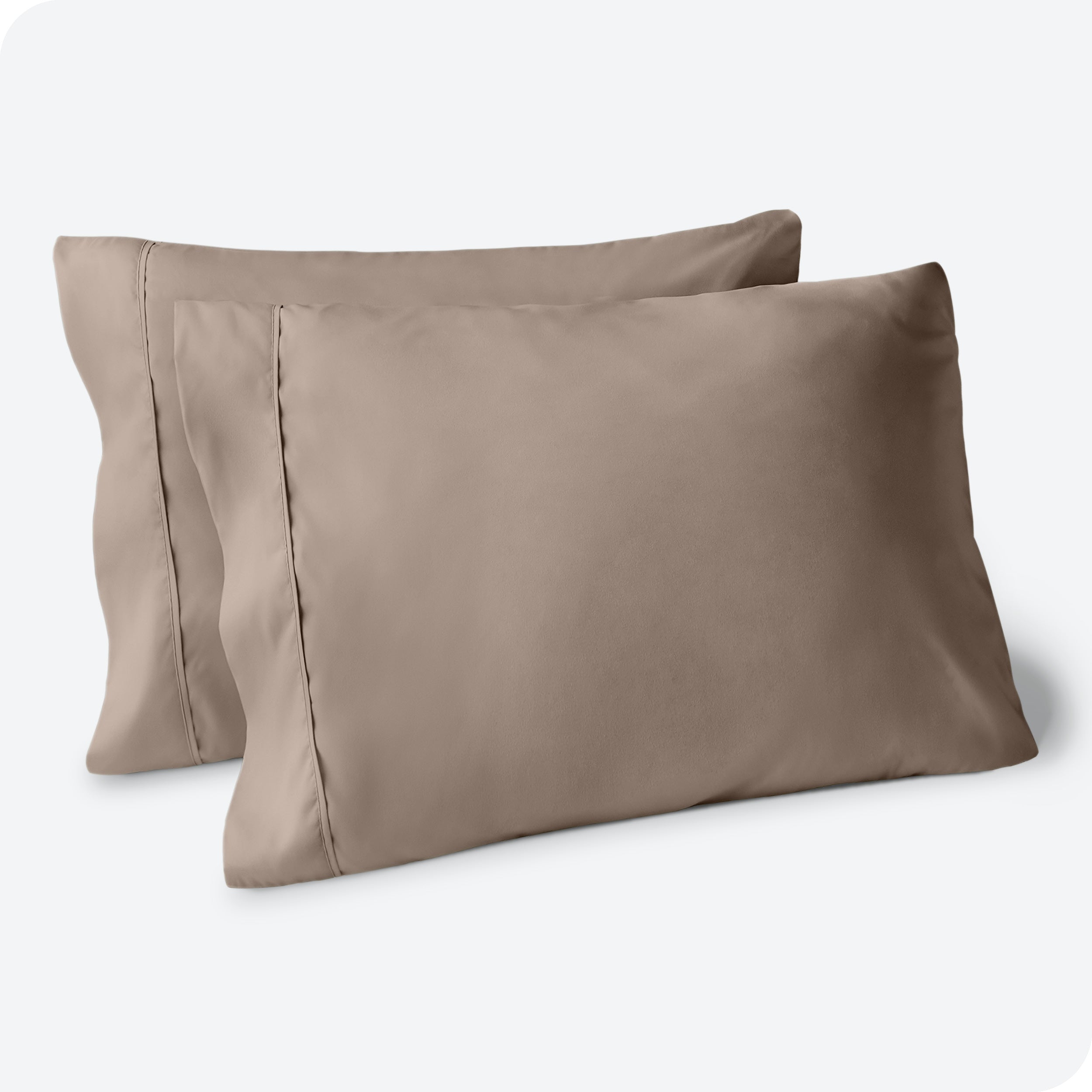 Two pillows on a white background with taupe pillowcases on them
