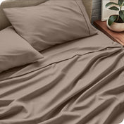 Bed sheets and pillows on a bed with a plant in the background