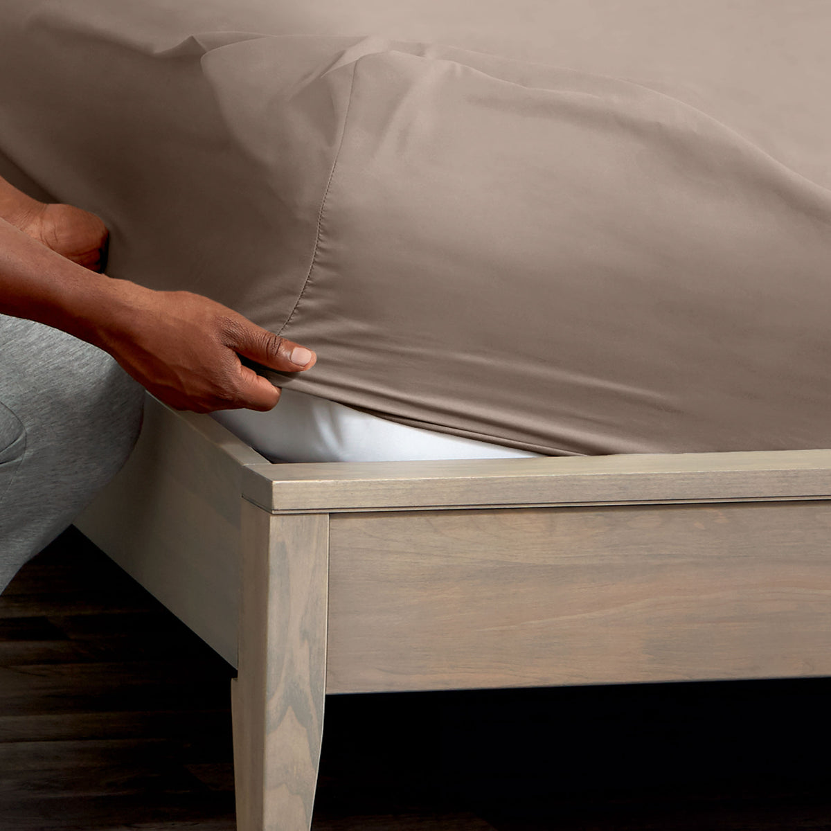 Person adjusting a fitted sheet on a mattress