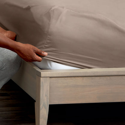 Person adjusting a fitted sheet on a mattress
