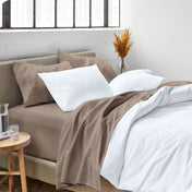 A modern bed made with a microfiber sheet set and duvet set. The duvet set and sheet set are folded over part way down the bed.