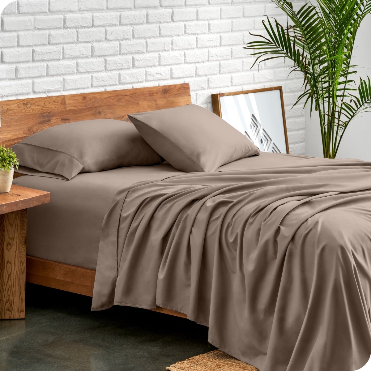 Bed with microfiber sheets against a white brick wall