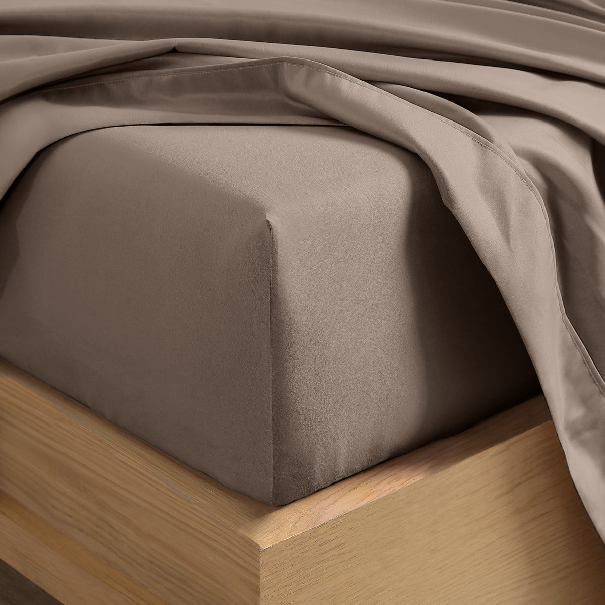 Close up of the corner of a mattress with a fitted sheet and flat sheet on it