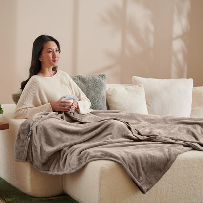 A woman sitting on a couch with a microplush blanket on her lap