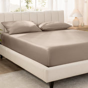 Bed with fitted sheet and pillowcases in a bright room.