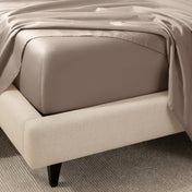 A close-up of the corner of a bed with a fitted sheet and matching flat sheet.
