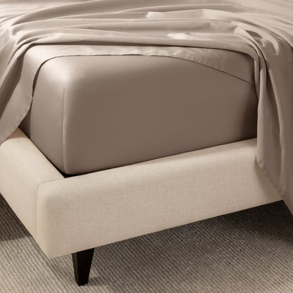 A close-up of the corner of a bed with a fitted sheet and matching flat sheet.