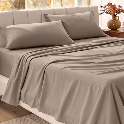 Bed sheets on a neatly made bed in a bright bedroom with large windows.