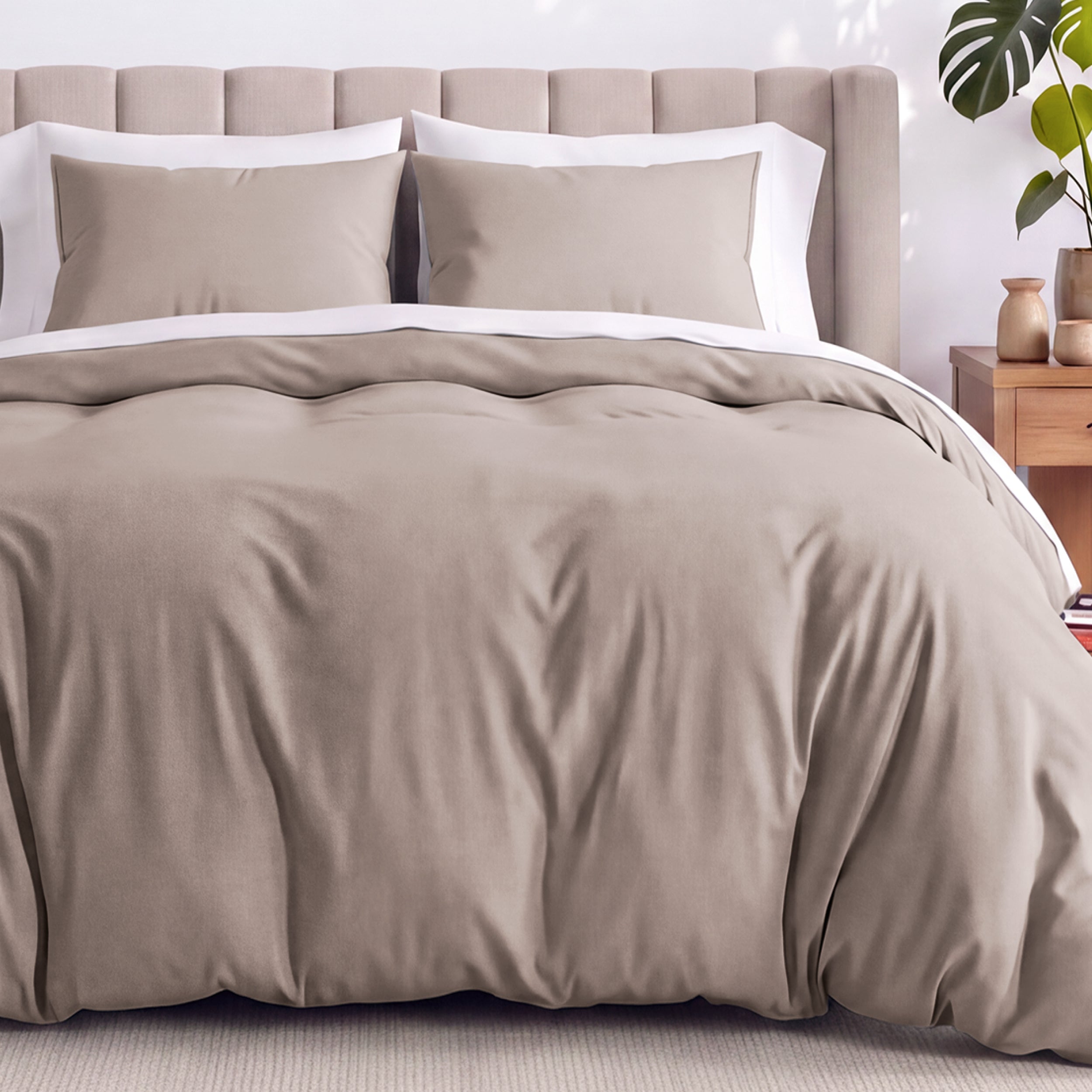 Neatly made bed with organic jersey bedding and pillow shams in a bedroom setting.