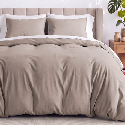Neatly made bed with organic jersey bedding and pillow shams in a bedroom setting.