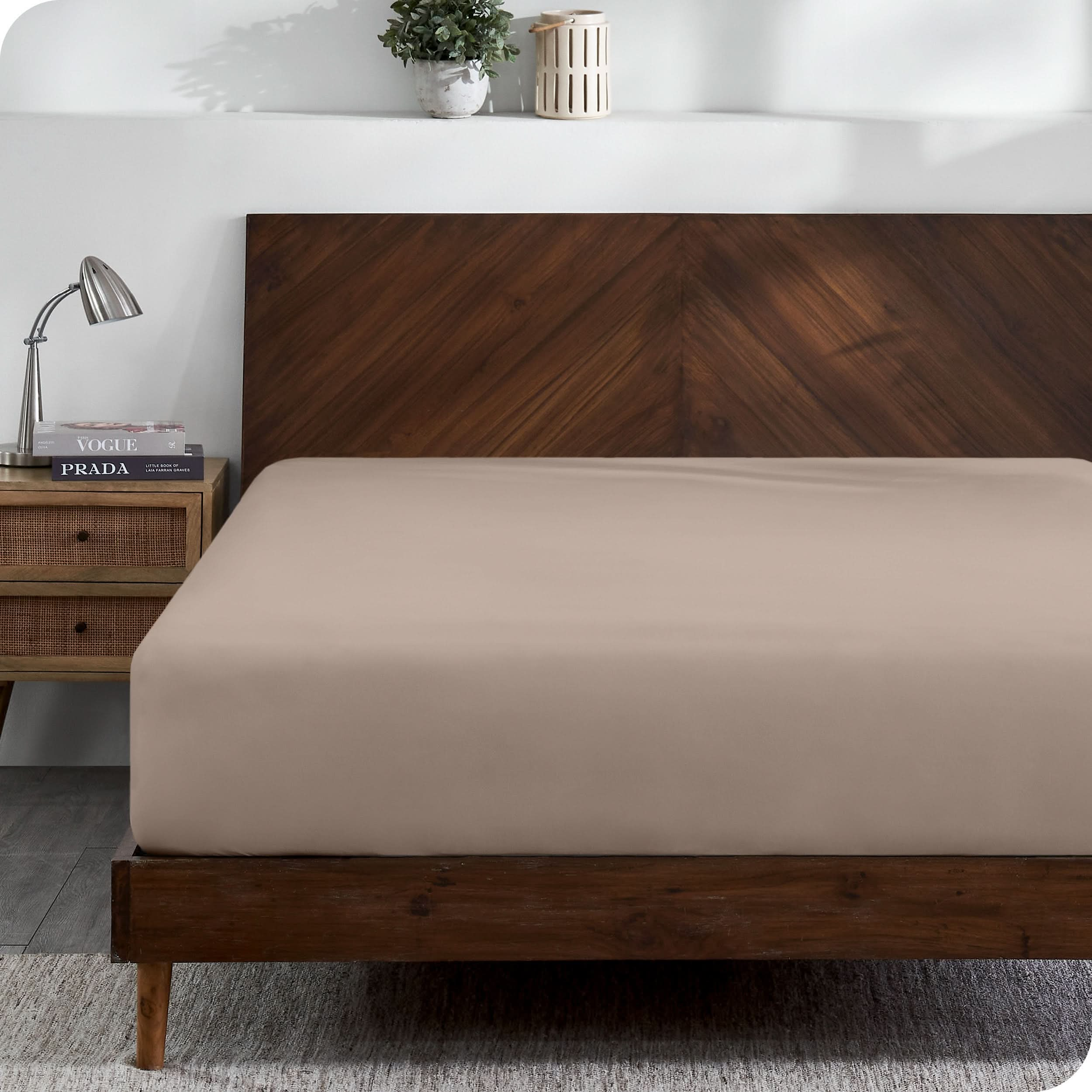 A modern wooden bed frame with a fitted sheet on the mattress