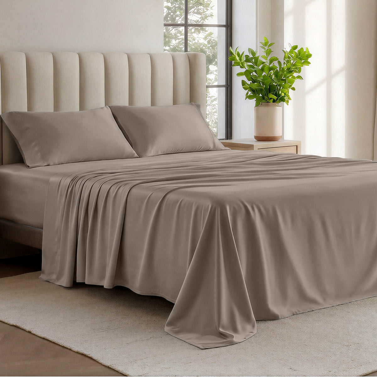 Organic cotton jersey sheets on a bed with a wicker headboard in a room with plants and a lamp.