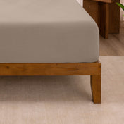 Fitted sheet on a wooden bed frame with a neutral background