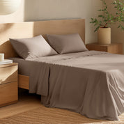 Bed with percale bedding and wooden headboard in a bedroom setting