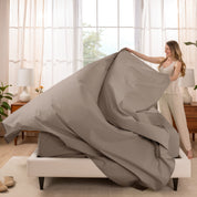 Woman putting a sheet set on a bed in a bright bedroom.