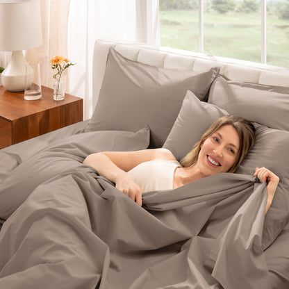 Woman lying in bed with percale bedding in a bright bedroom