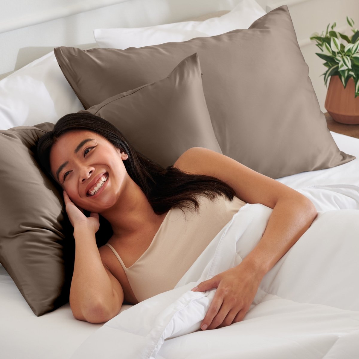Woman lying on a bed with satin pillows and white bedding