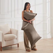Woman holding 2 pillows with satin pillowcases on them