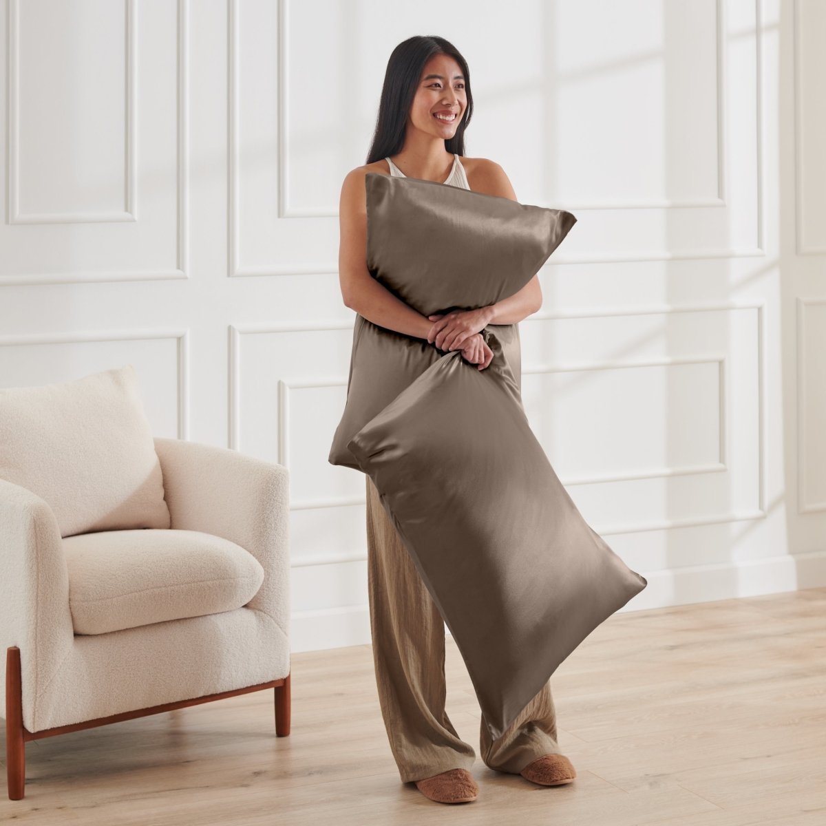 Woman holding 2 pillows with satin pillowcases on them