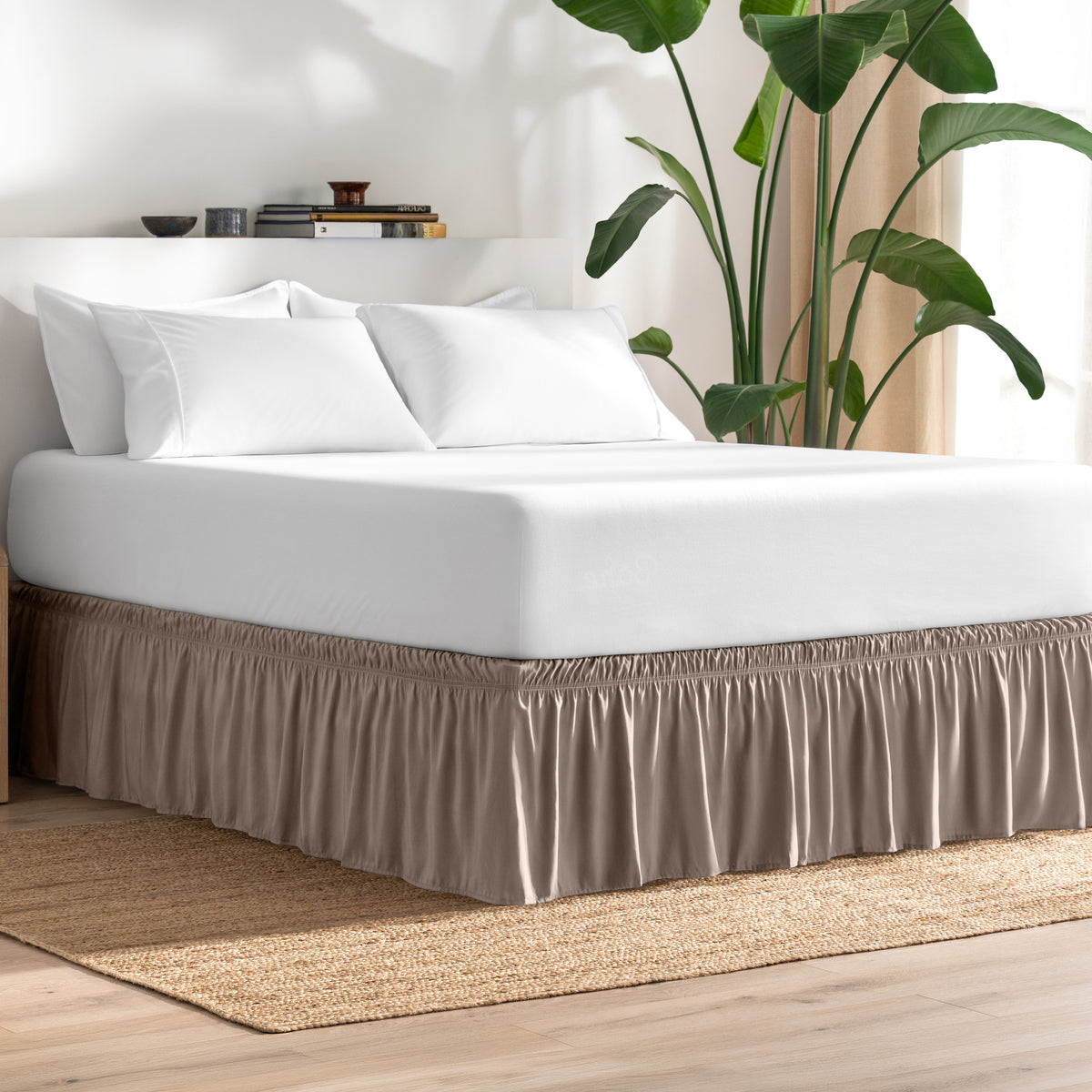 Bed with bed skirt, white bedding, and a plant in a room.