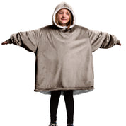 A child is wearing a sherpa wearable blanket and is standing with her arms stretched out.
