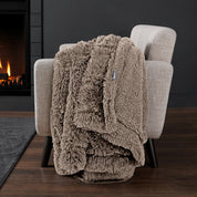 Sherpa blanket draped over an armchair in front of a fireplace.