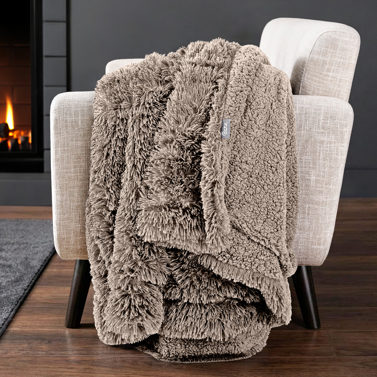 Sherpa blanket draped over an armchair in front of a fireplace.