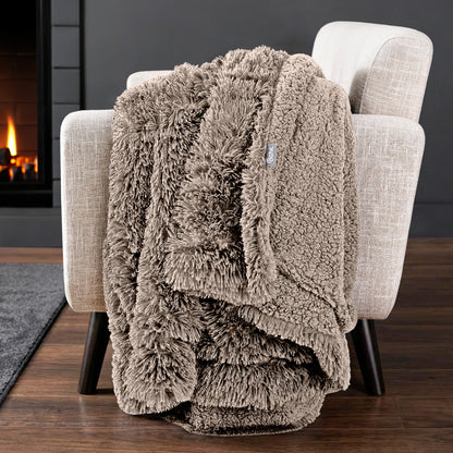 Sherpa blanket draped over an armchair in front of a fireplace.