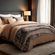 Neatly made bed and a textured throw blanket  over the end of the bed.